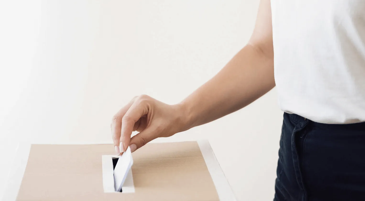 A person putting a voting ballot in a box